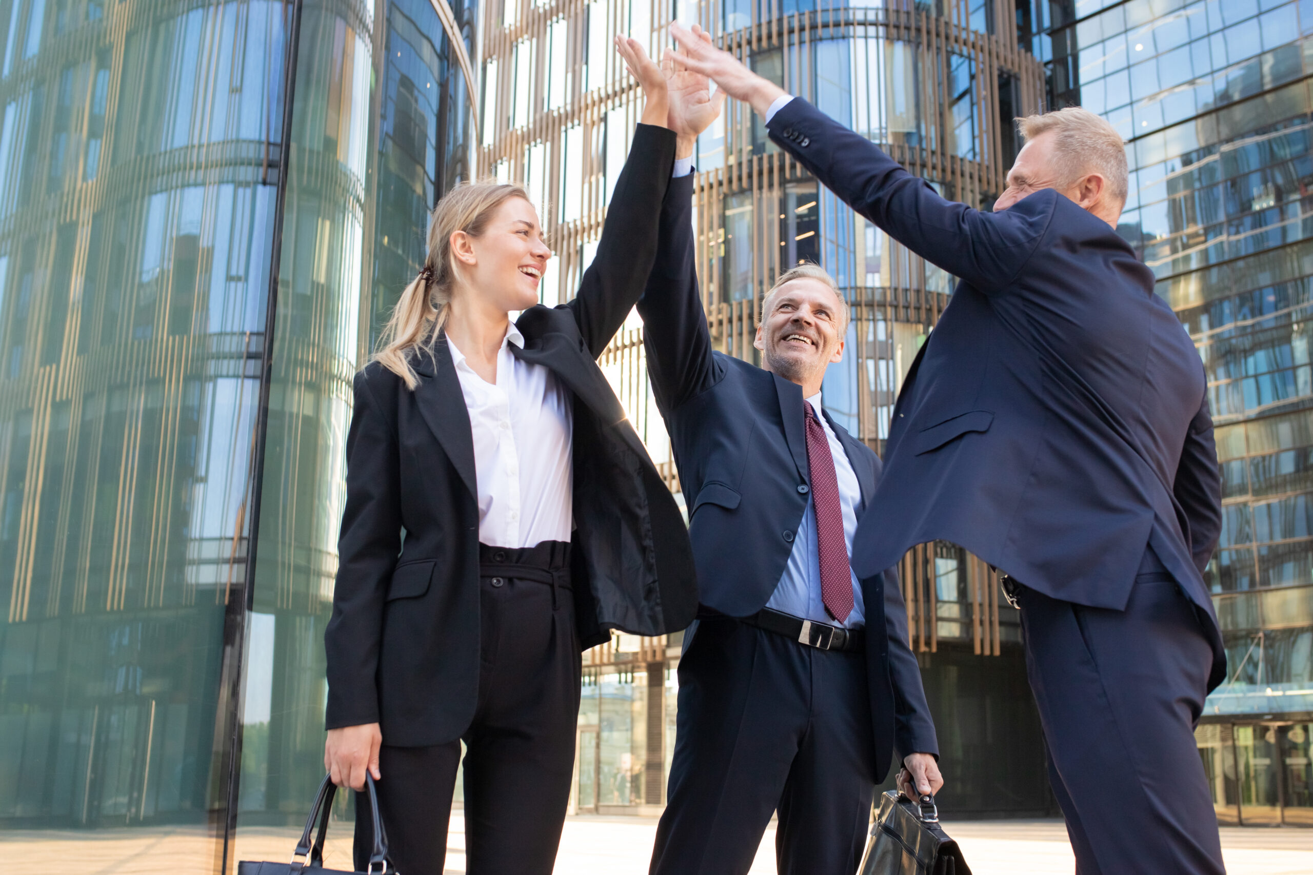 Three cheerful businesspeople giving five and smiling